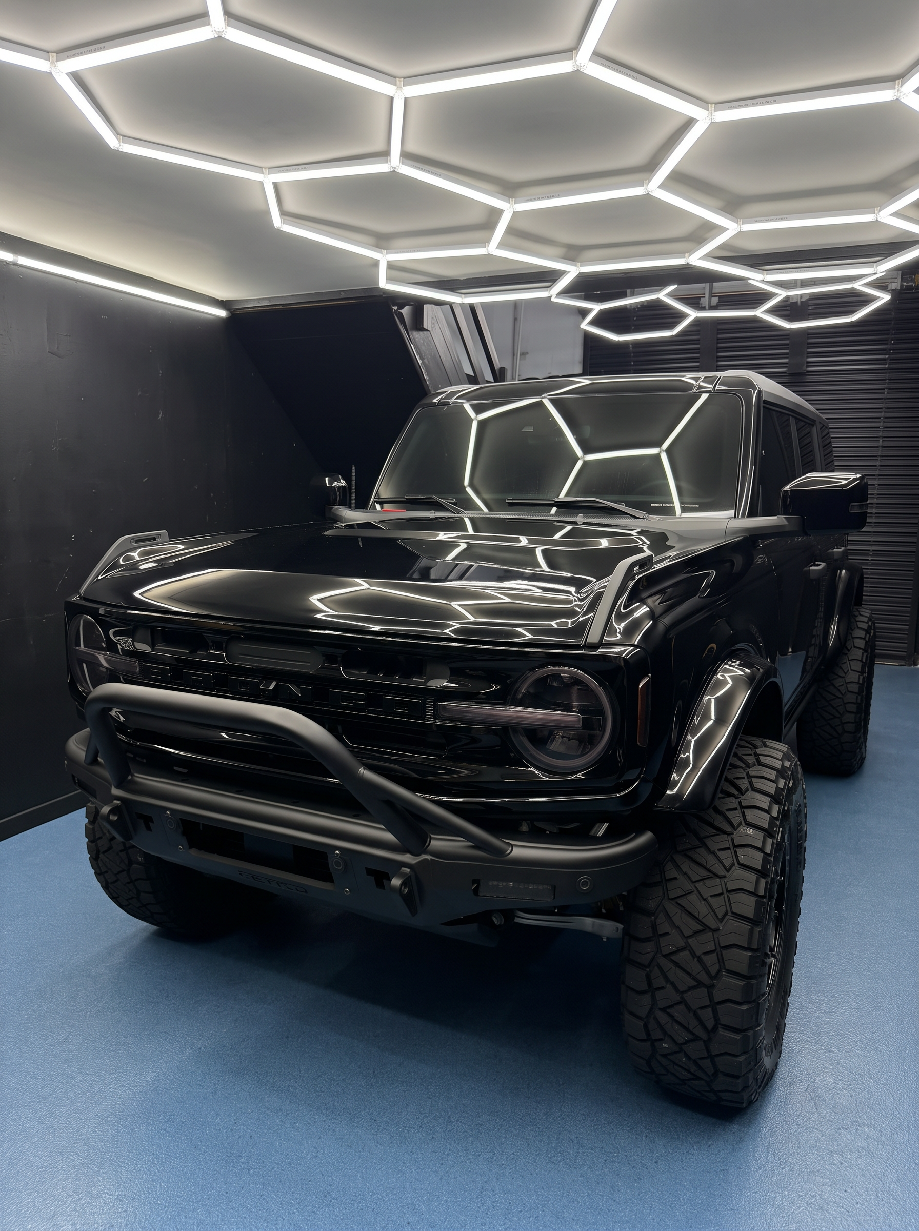 Gloss-black Ford Bronco beneath the shop's inspection lights