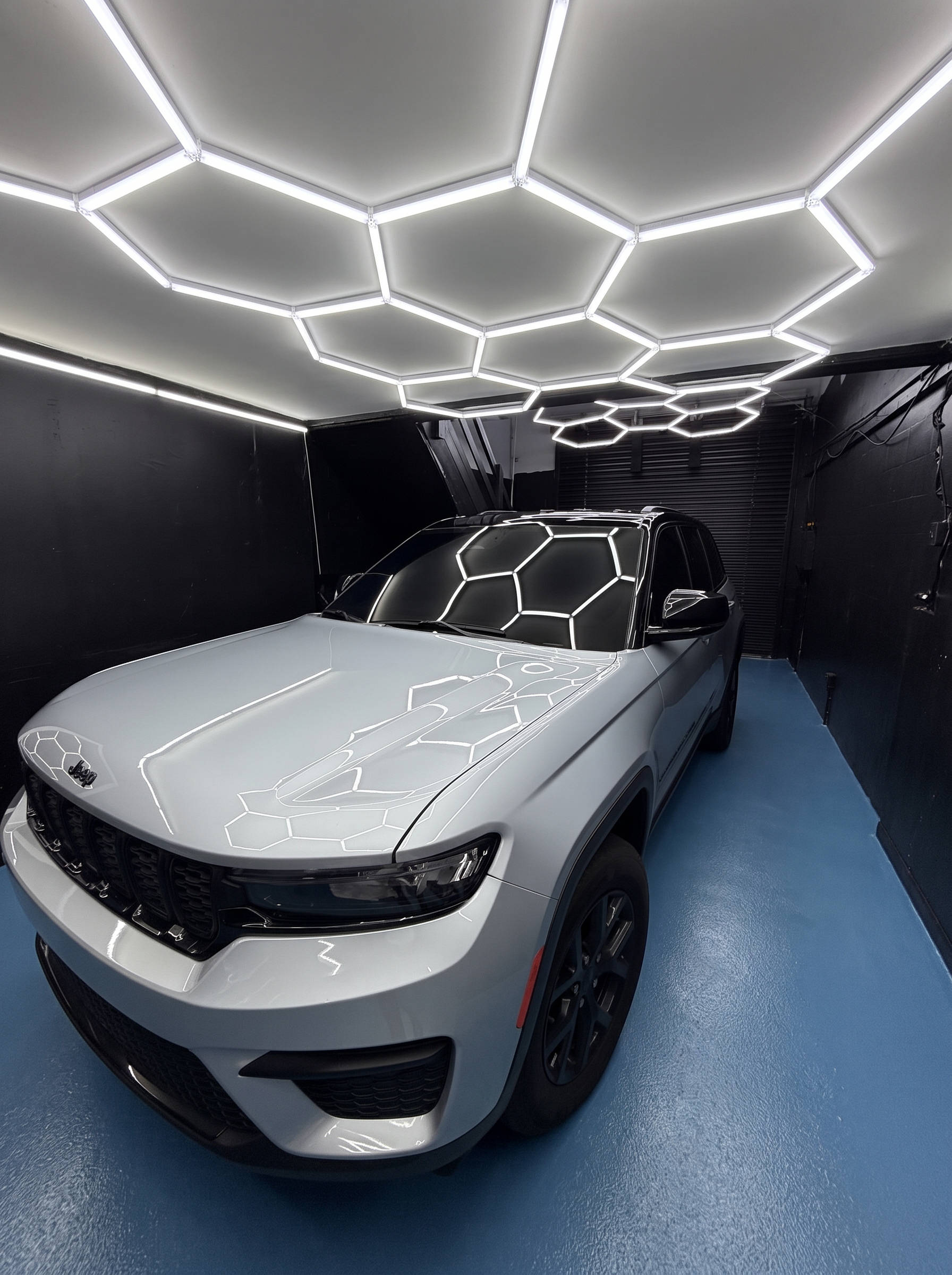 White Jeep Grand Cherokee beneath the shop's hexagonal lights